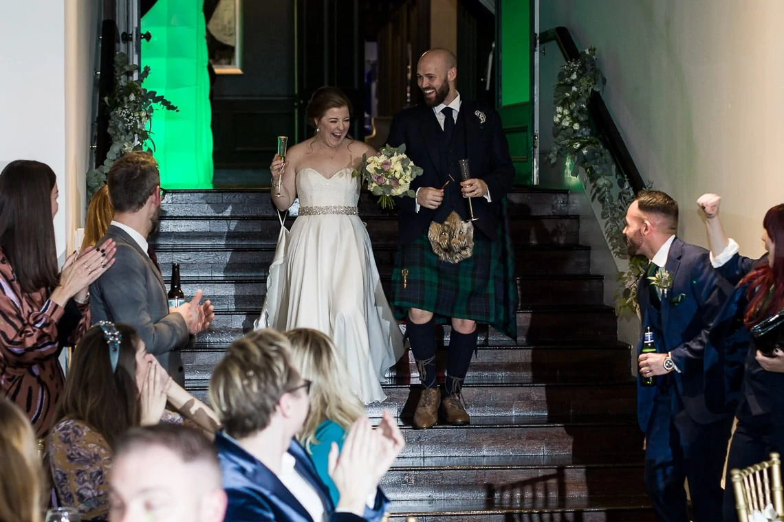 bride and groom are announced into The Orangery and walk down the steps for the evening reception