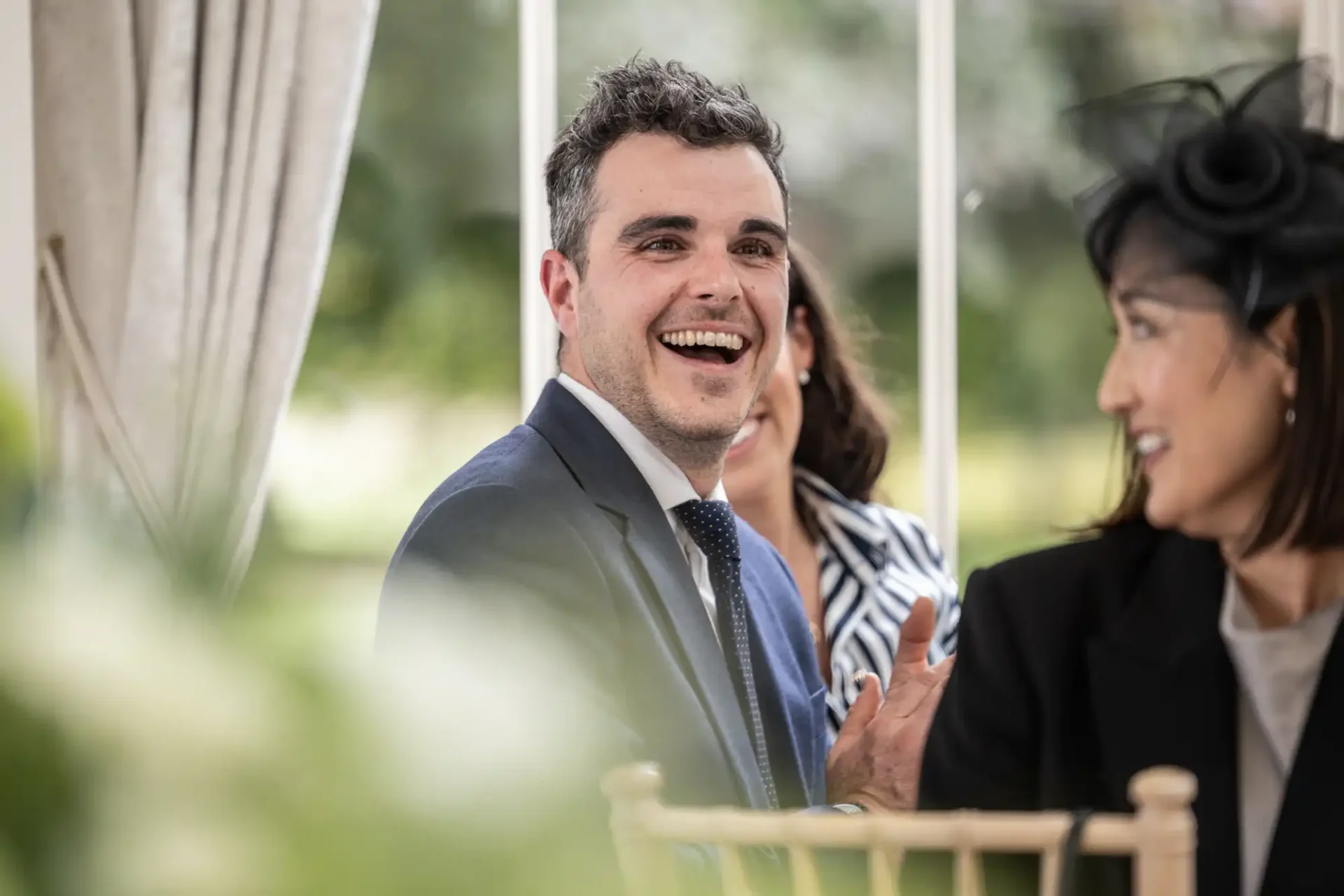 Man in a suit smiling at an event with people around.