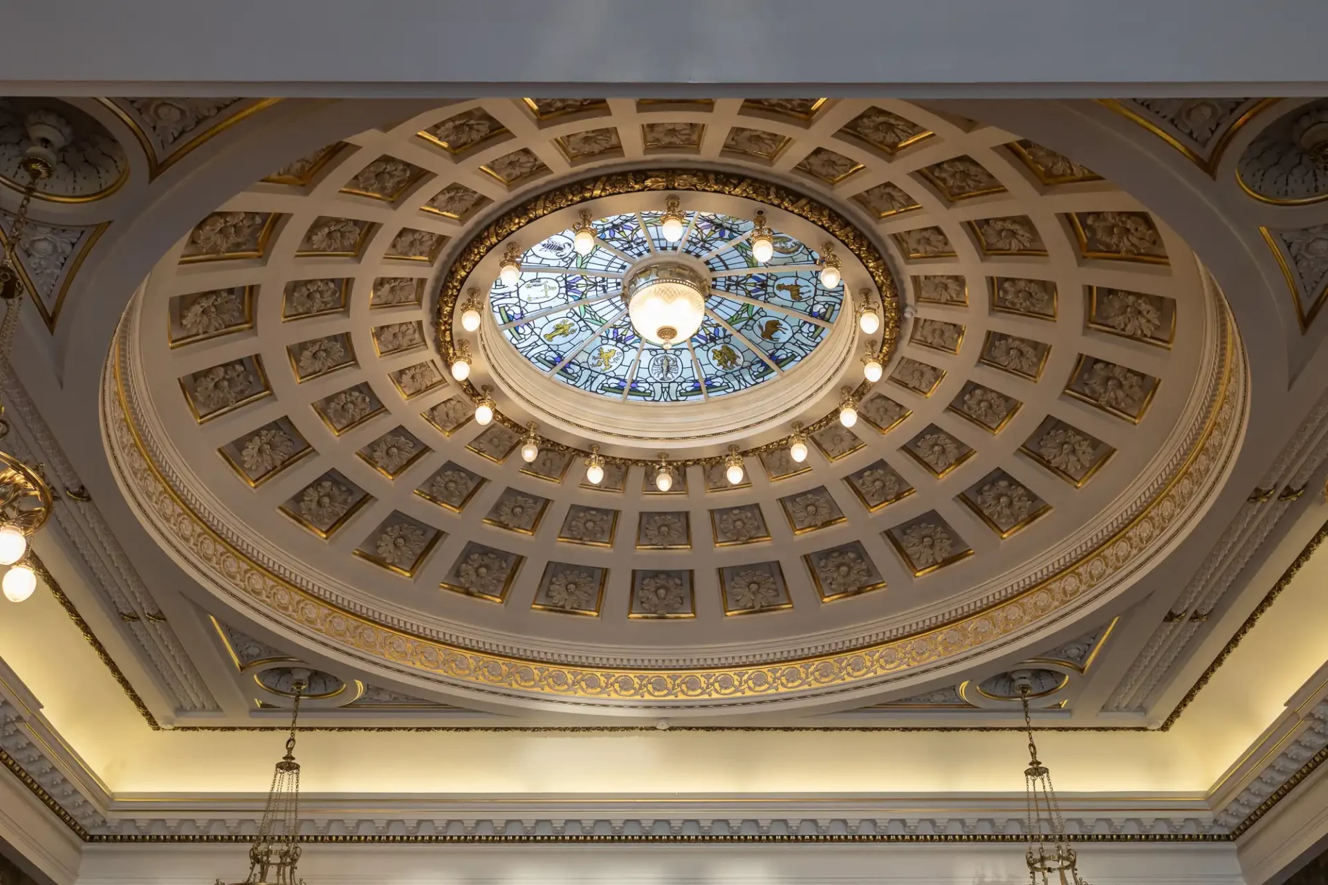 Ornate dome ceiling with intricate patterns, a central chandelier, and stained glass detail.