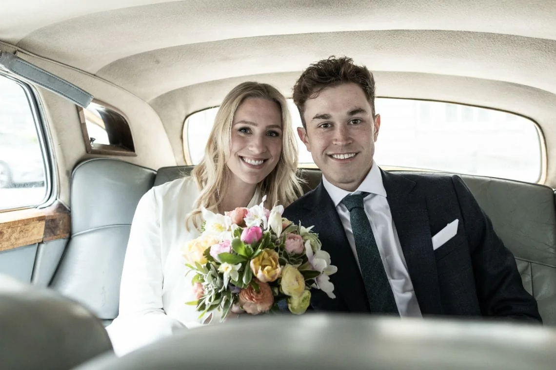 Bride and groom sitting in the back of a classic car