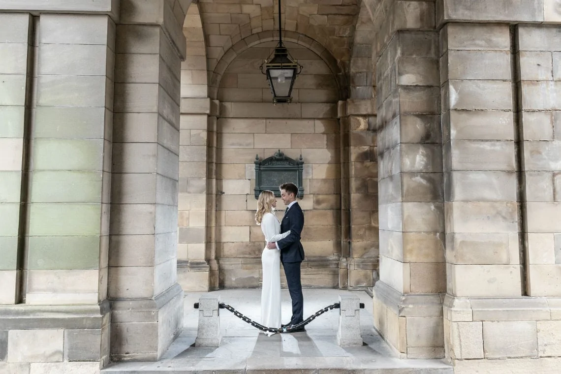 newlyweds embrace under the arch at the entrance to the Quadrant