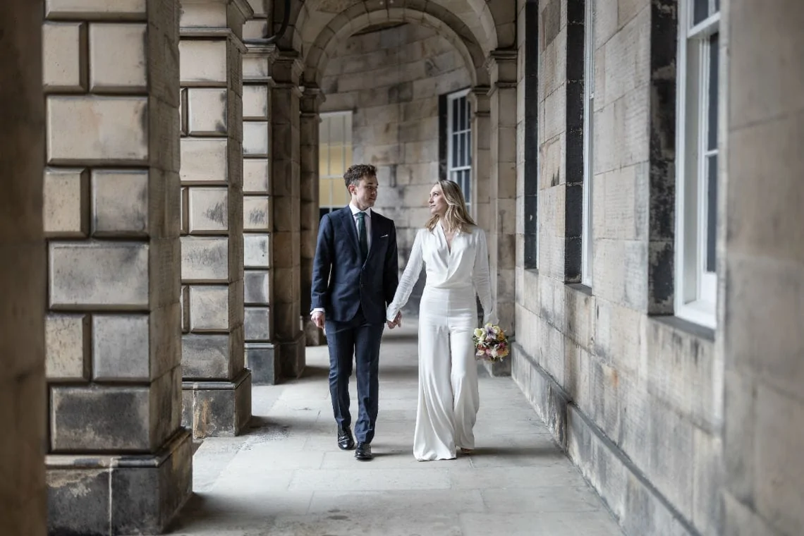 bride and groom holding hands under the arches at the Signet Library