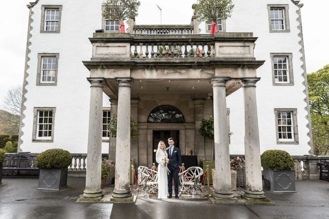newlyweds embrace under the entrance canopy at Prestonfield House