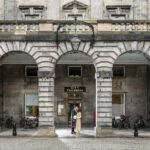 newlyweds embrace under the arches of the Quadrant at City Chambers in the rain