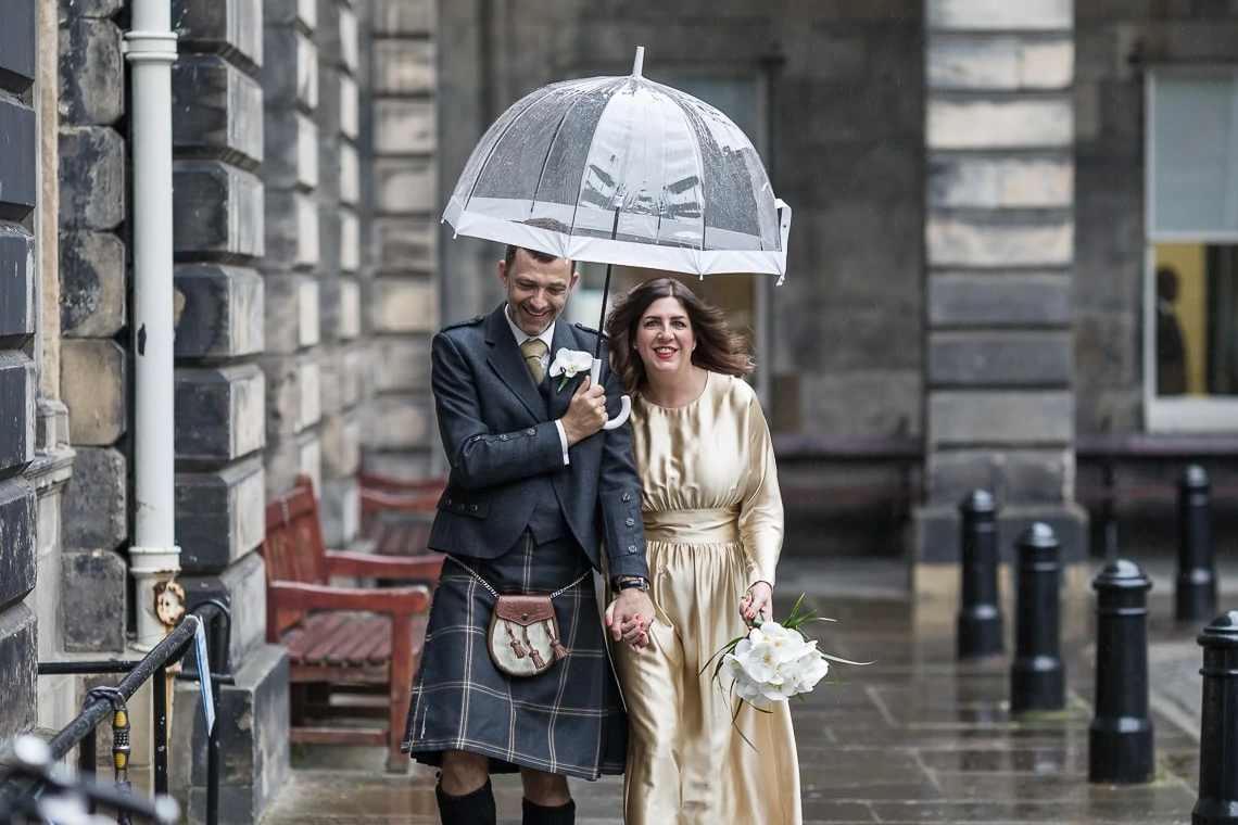 newlyweds walking under an umbrella at The Quadrant