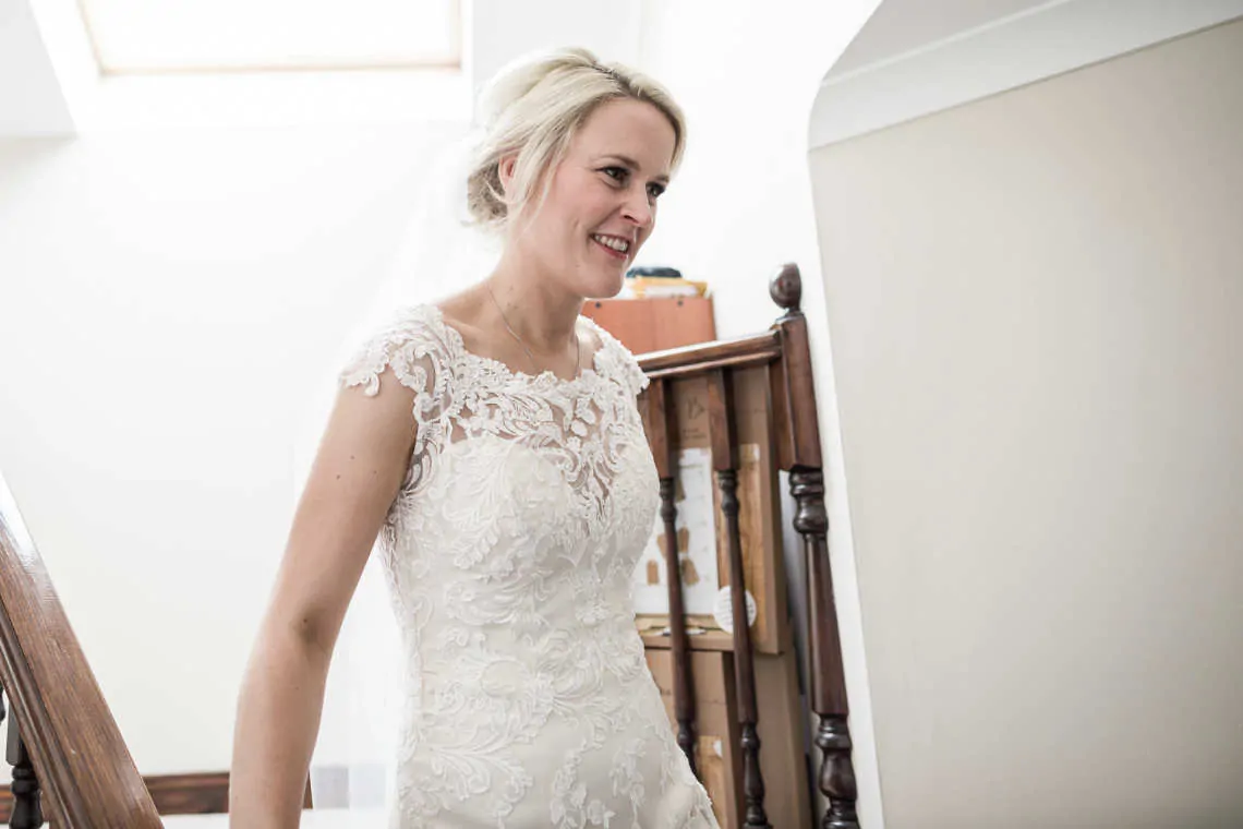 First look of bride in wedding dress walking down stairs