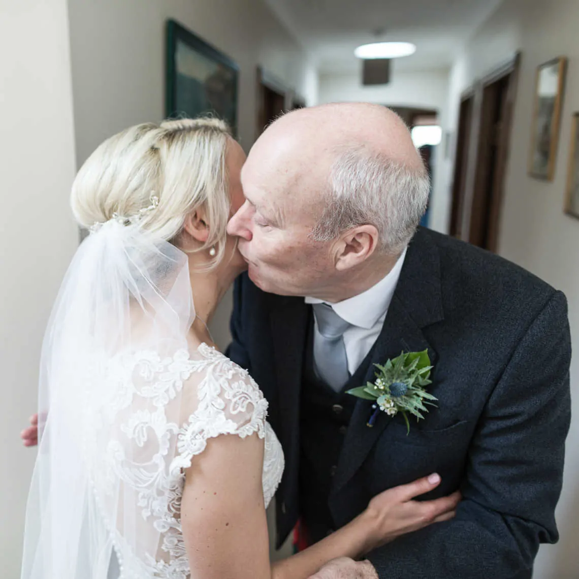 Father of the bride kissing the bride on her cheek