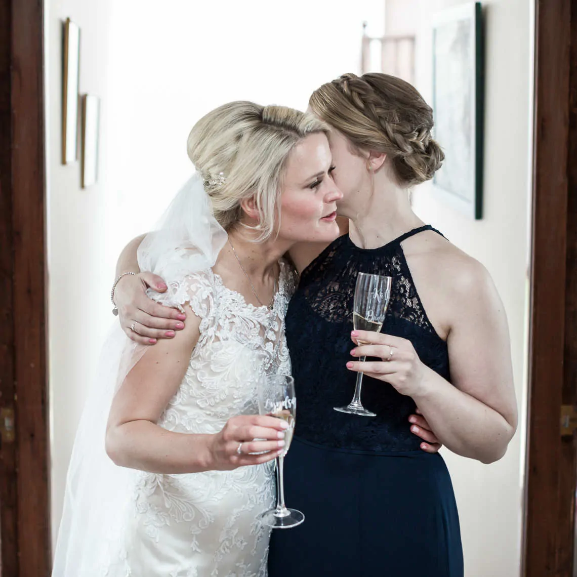 Bridemaid kissing bride at her parents home