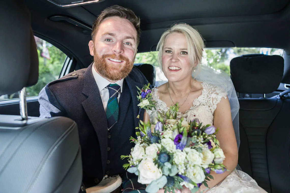 Bride and groom smiling in the wedding car
