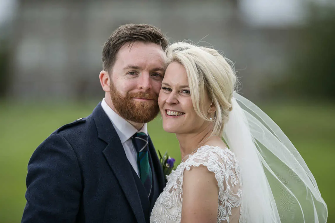 Portrait of newlyweds in front of blurred Dalmahoy Hotel
