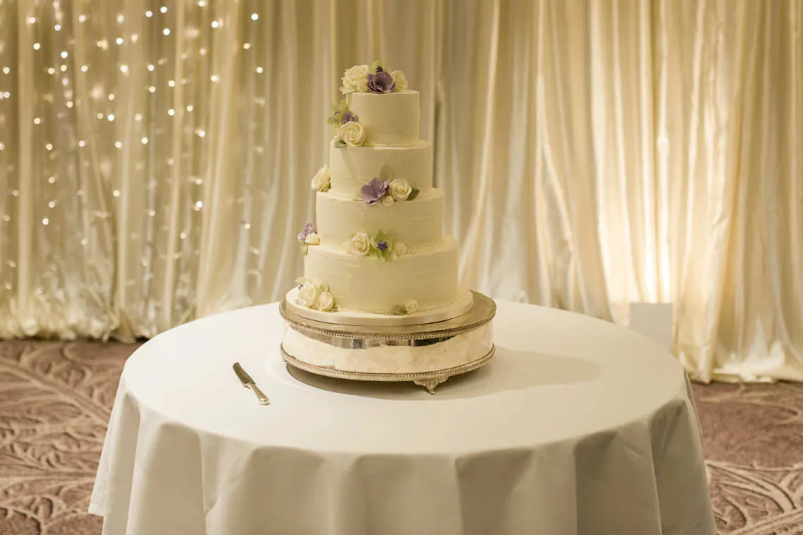 Four tiered wedding cake with flowers on silver cake stand