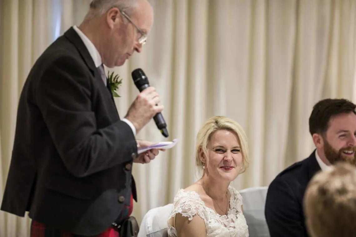 Bride laughing as her Dad gives his wedding speech at reception