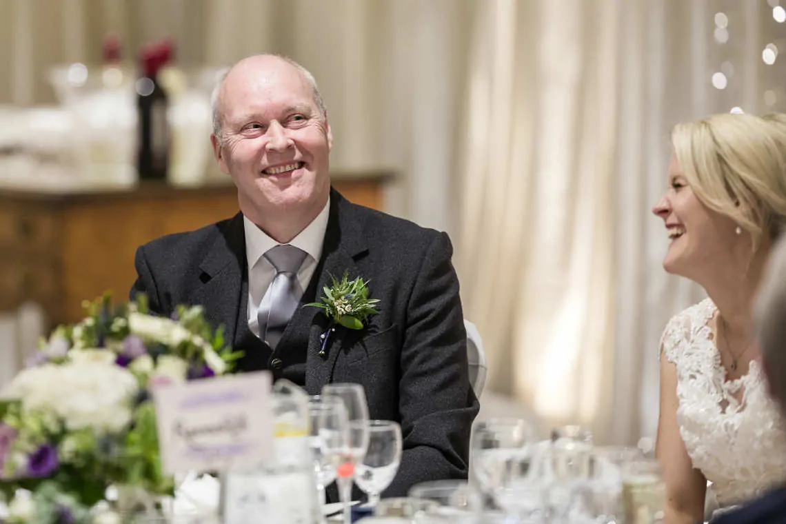 Father of the bride laughing during speeches at reception