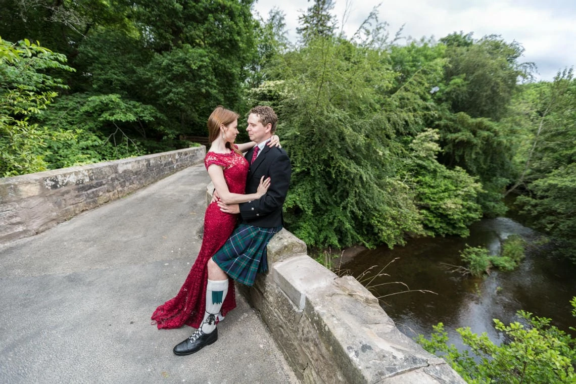 newlyweds embrace on the arched bridge with the river in the background