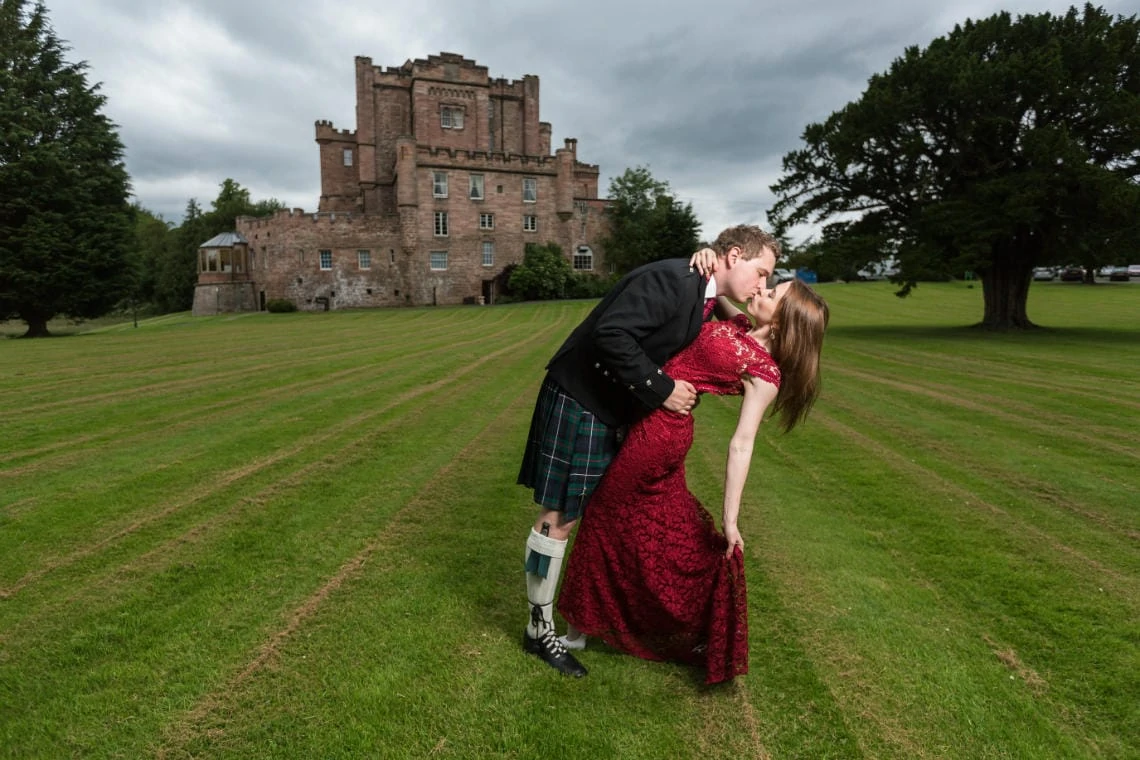 bride and groom kissing on the lawn in front of the castle
