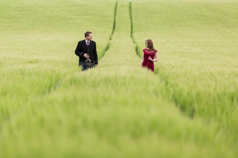 newlyweds walking along the tracks through a corn field near the castle