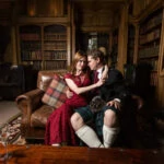 newlyweds embrace sitting on a leather sofa in the Library