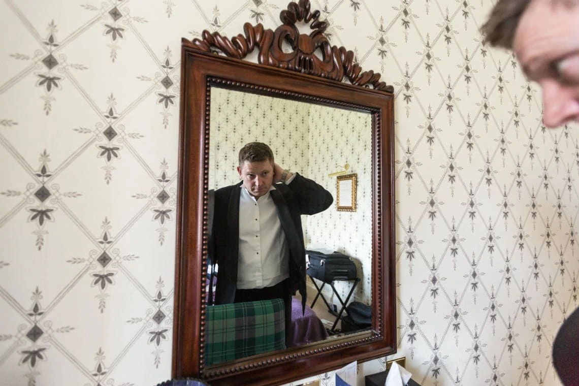 best man getting ready in front of a bedroom mirror