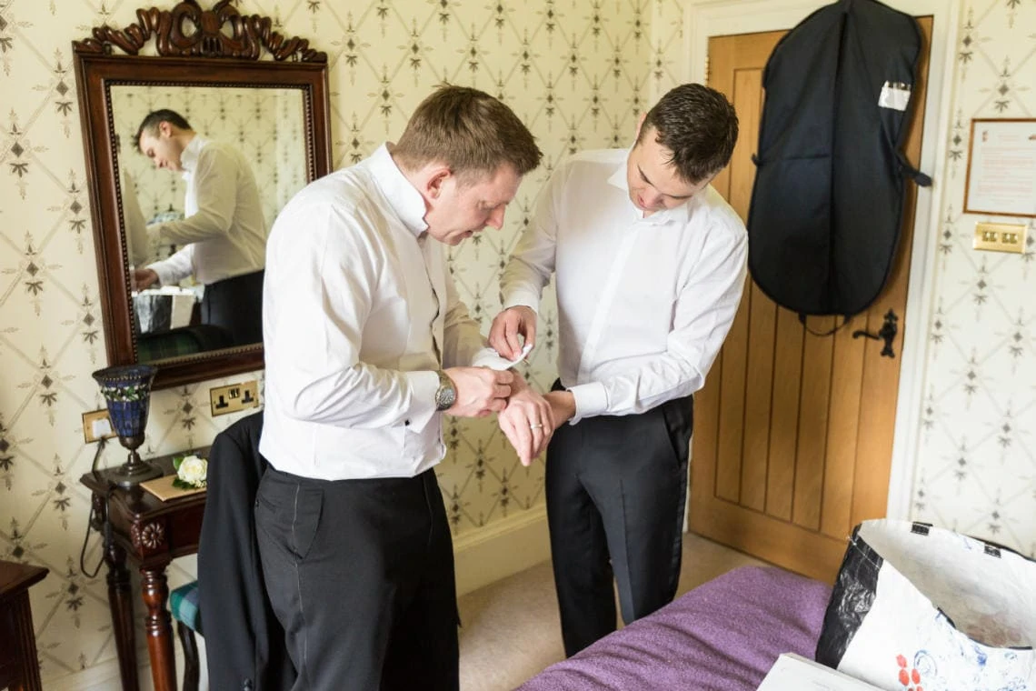groom helps best man put on his cuff links