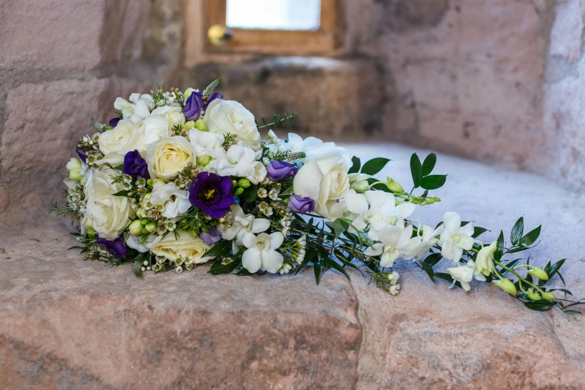 bridal bouquet of white and purple flowers sitting on the stone window sill