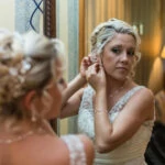 bride putting in her earrings in front of a mirror in the bedroom
