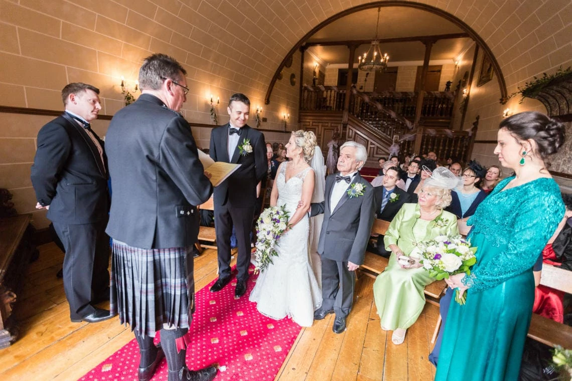 bride and groom smiling while looking at each other in the chapel, viewed from the front