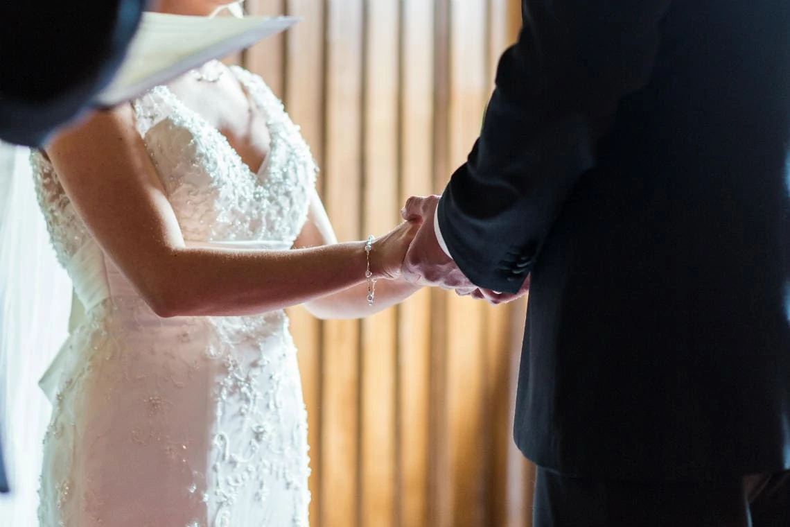couple holding hands during their exchange of vows in the chapel