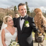groom holding an eagle on the castle patio as his bride watches
