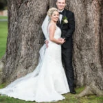 newlyweds embrace in front of the old tree on the lawn in front of the castle