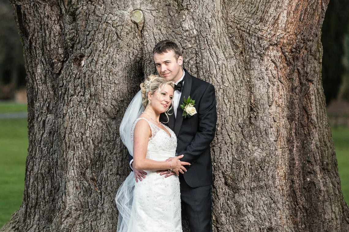 newlyweds embrace in front of the old tree on the lawn in front of the castle