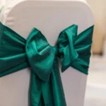 white chair covers with dark green ribbon tieback