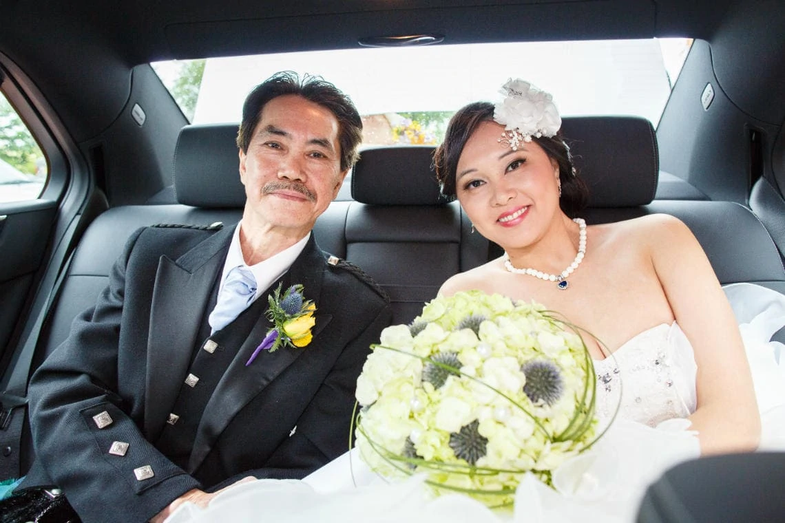 bride and her father sitting in the car to take them to Dalhousie Castle