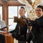bride, groom, best man and celebrant smiling as the owl delivers the rings