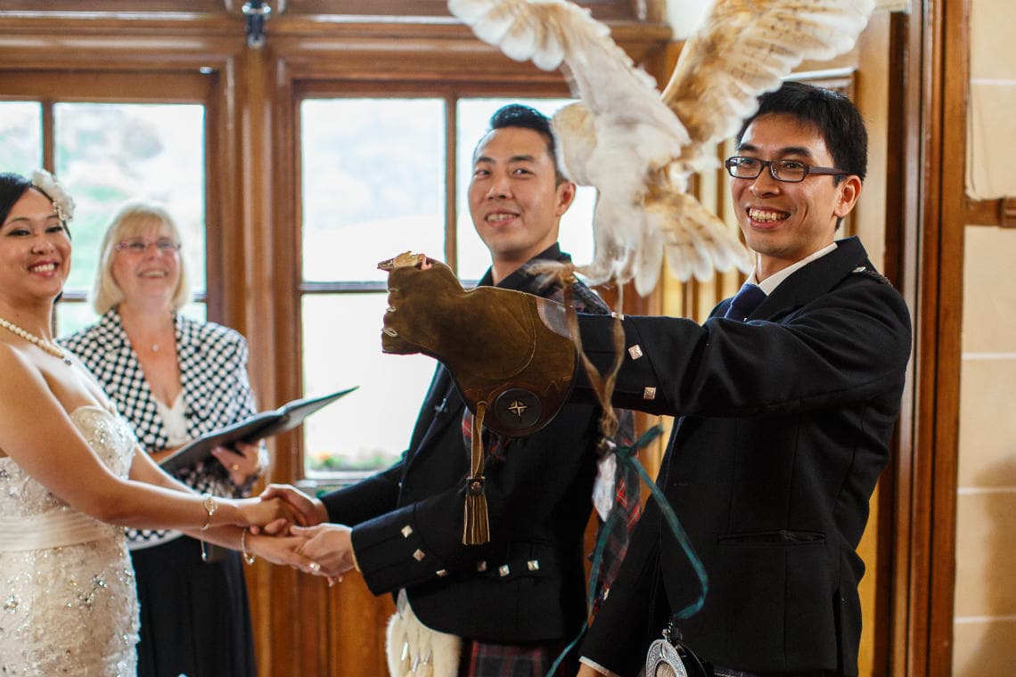 bride, groom, best man and celebrant smiling as the owl delivers the rings