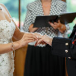 bride places ring on groom's finger in the chapel