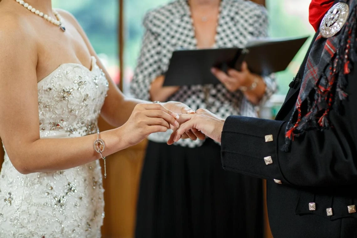 bride places ring on groom's finger in the chapel