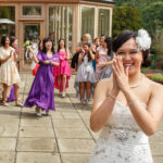 female guest catches the bride's bouquet on the castle's patio