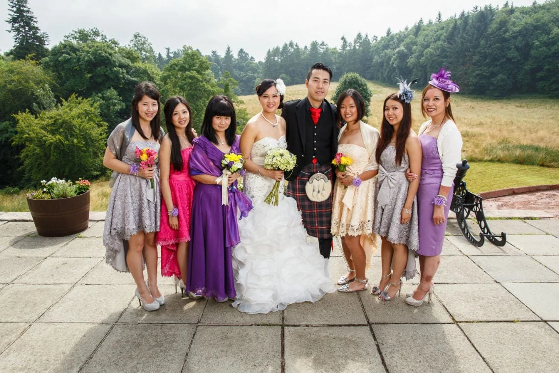 newlyweds and female guests group photo on the castle patio