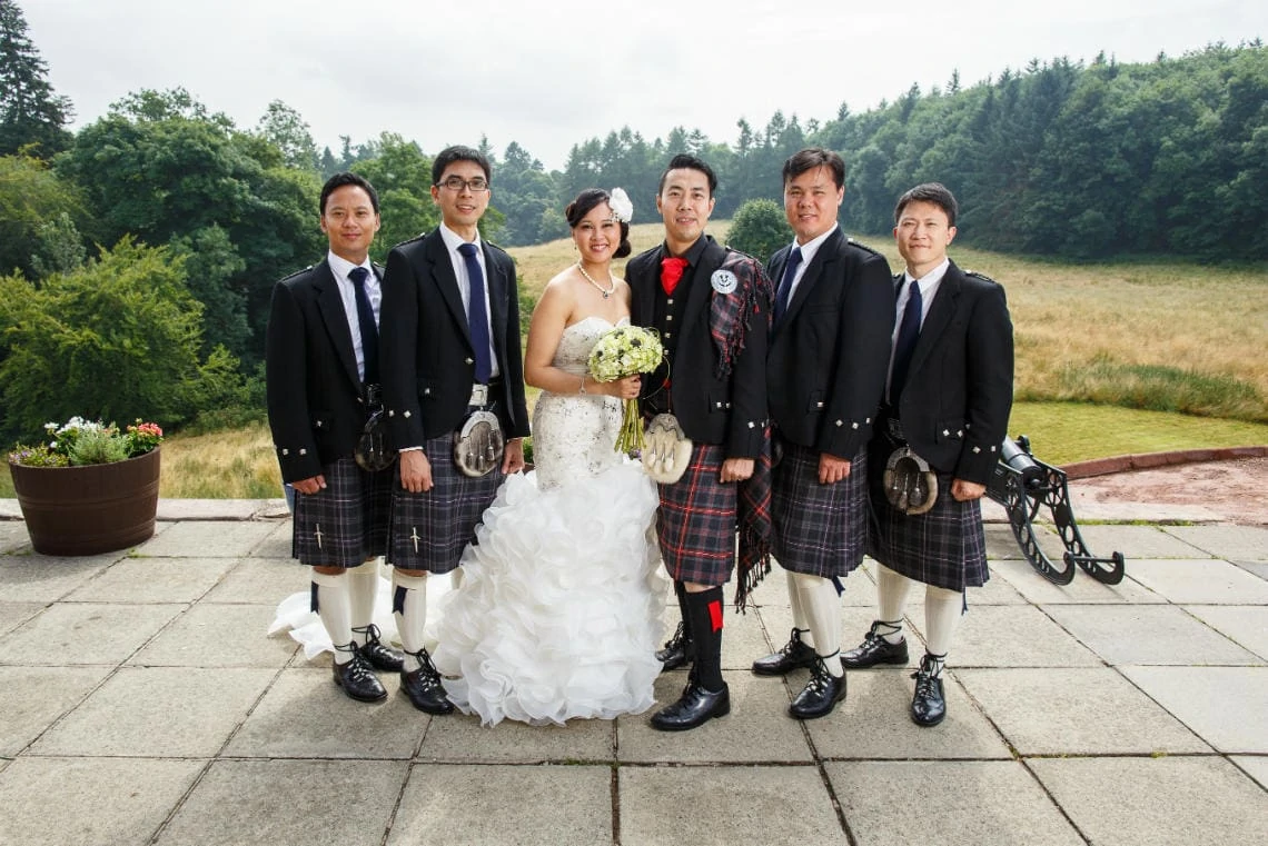 newlyweds and male guests group photo on the castle patio