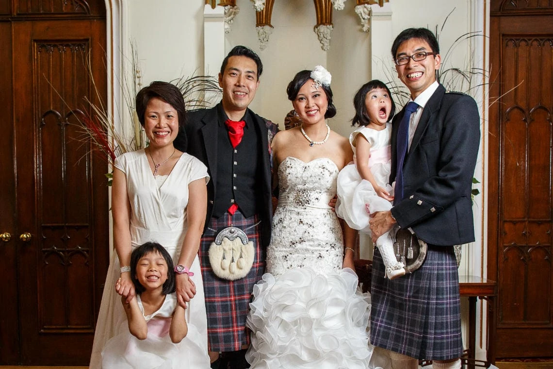 newlyweds and family group photo in the reception area of the castle