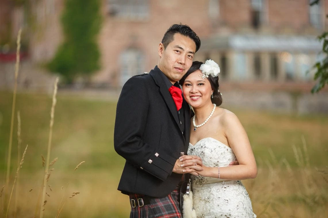 newlyweds embrace in the meadow with the castle in the background