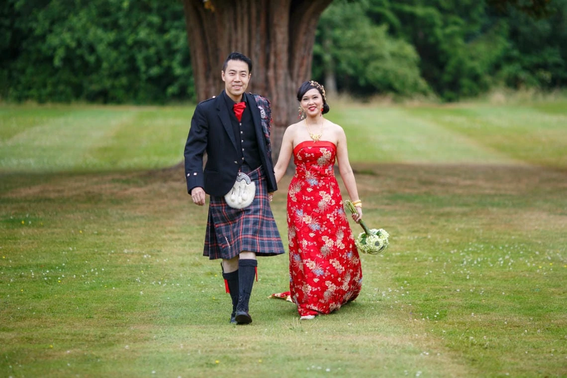 groom and bride holding hands as they walk across the lawn