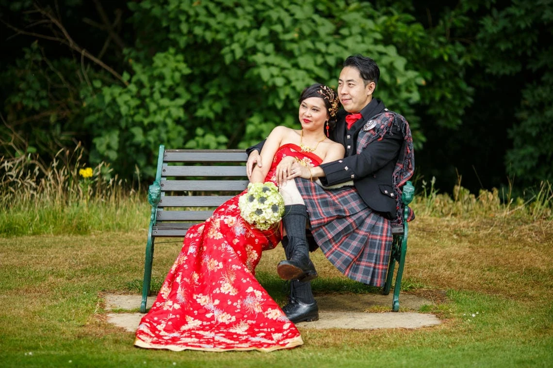 bride and groom sitting on a chair on the lawn