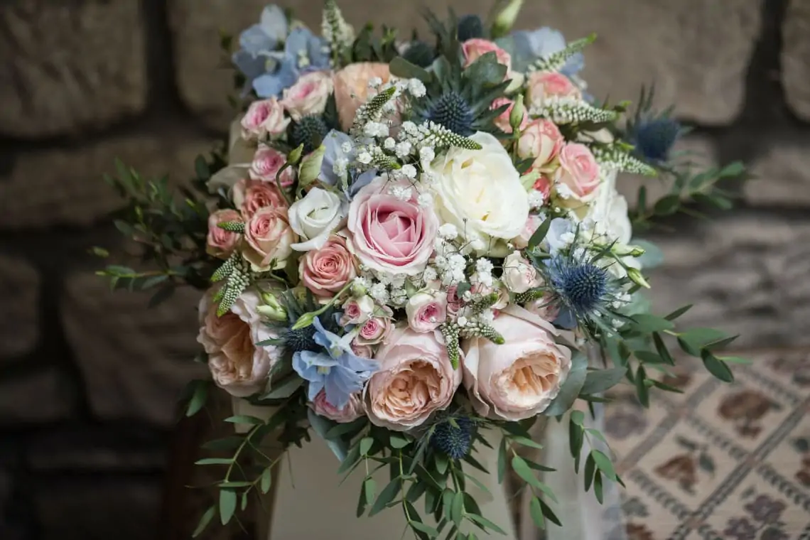 Close up of bridal wedding bouquet with pink and white roses and thistles.