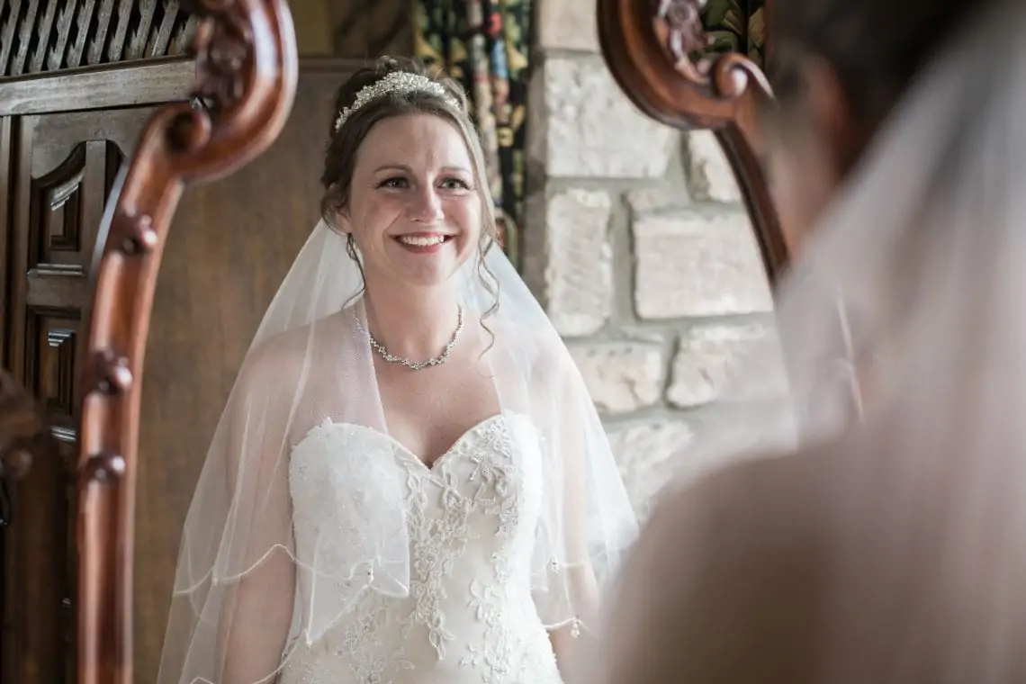 Smiling bride looking in a mirror.