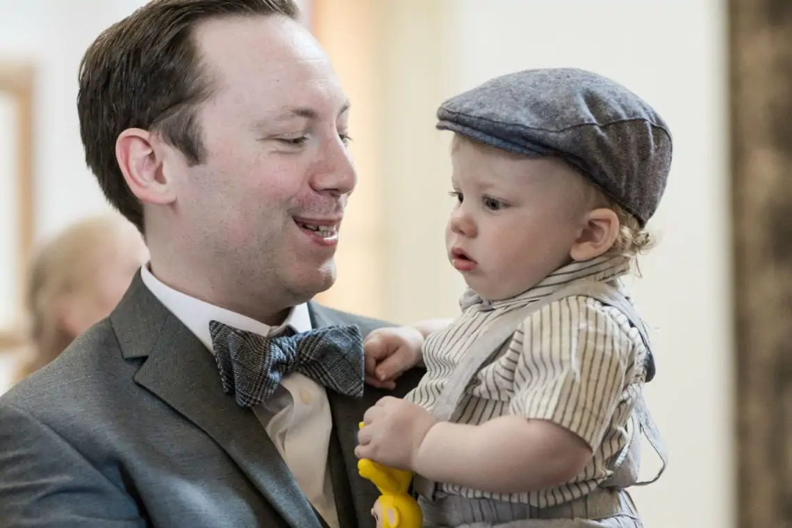 Man holding baby wearing flat cap.