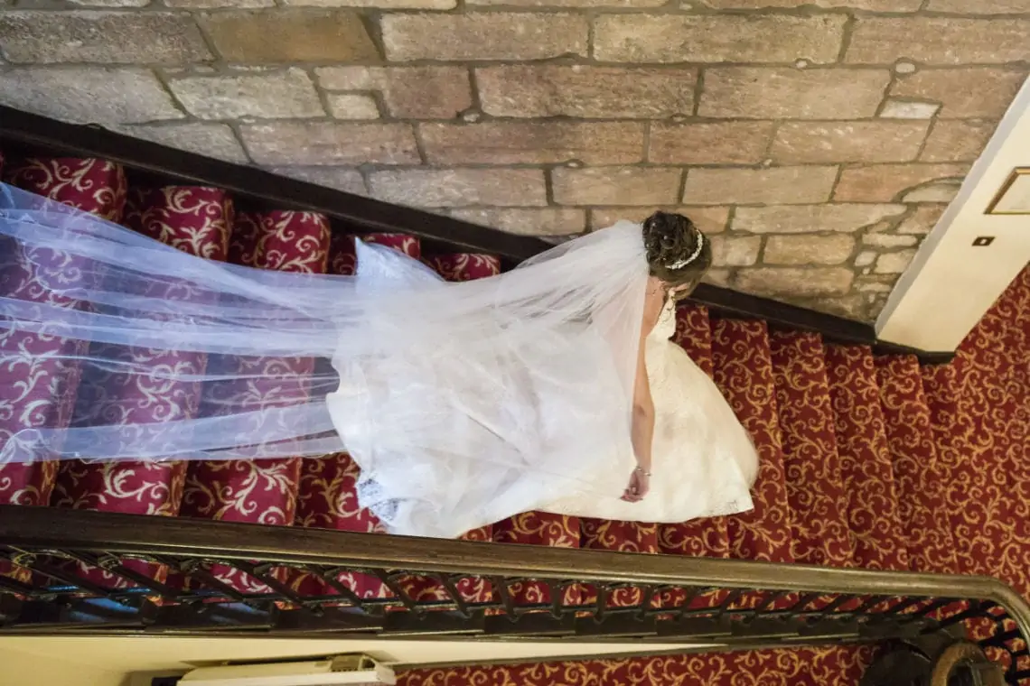 Shot taken from above of bride walking down staircase in the castle.
