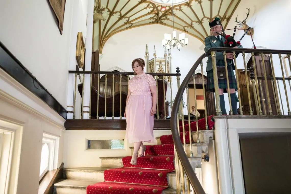 Bridesmaid walking down stairs in castle.