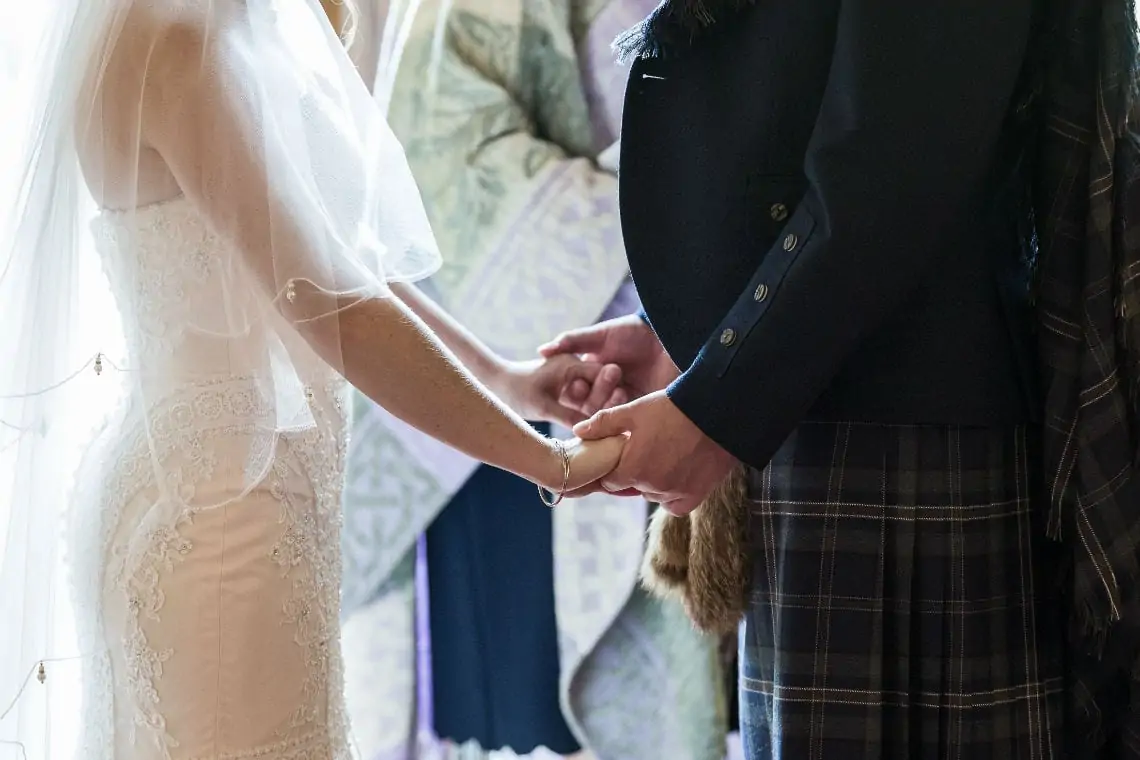 Bride and Groom holding hands at marriage ceremony.