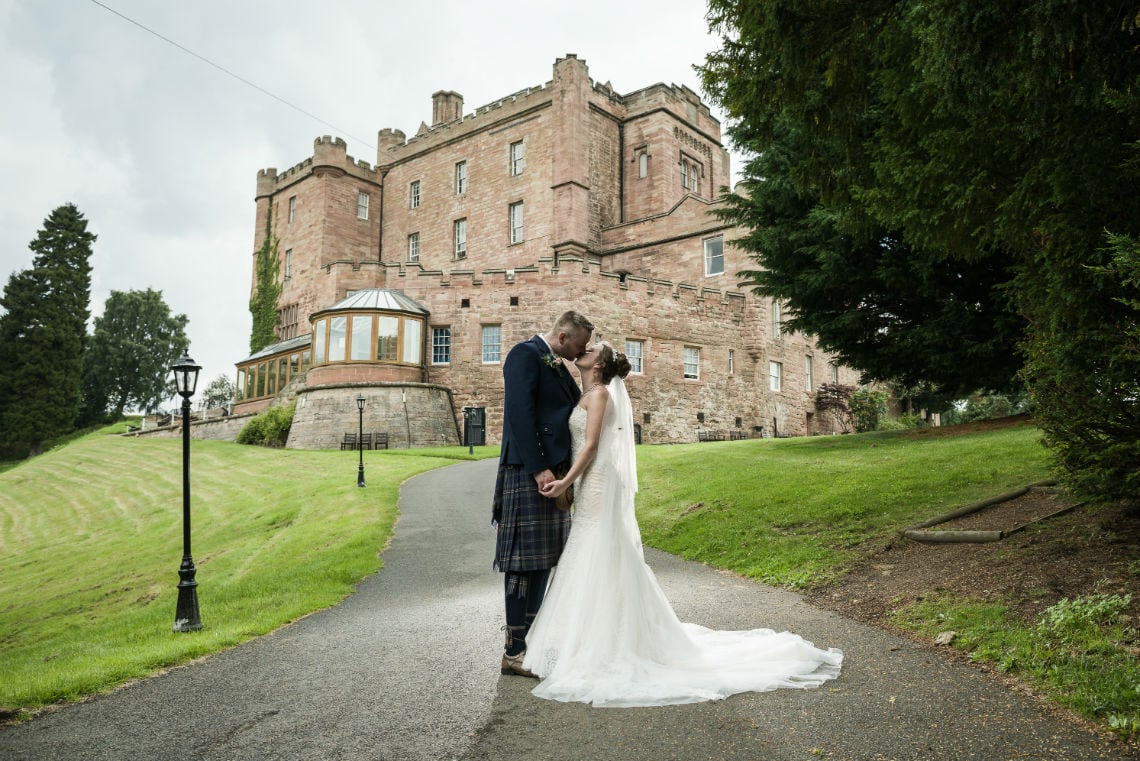 Bride and Groom kissing in front of castle.